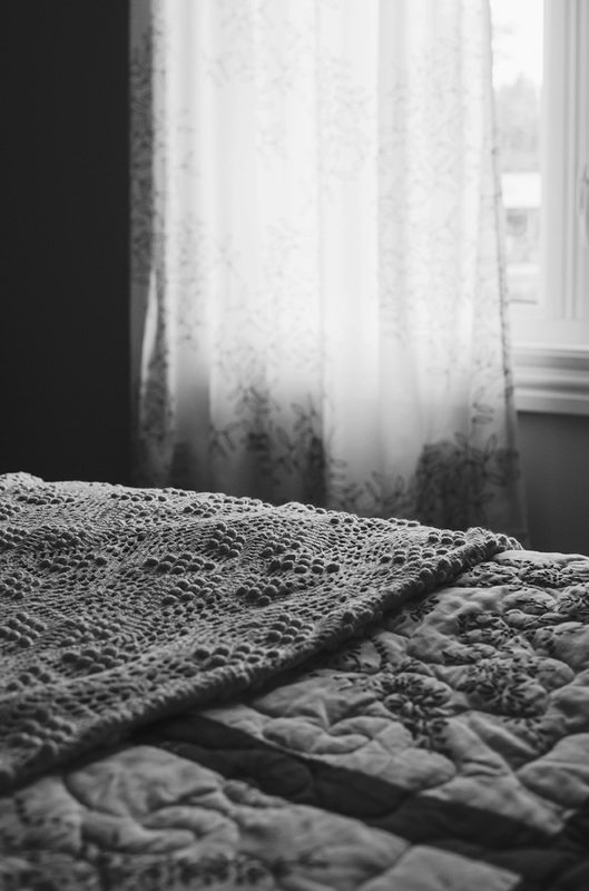 Black and White picture of curtain and crocheted blanket