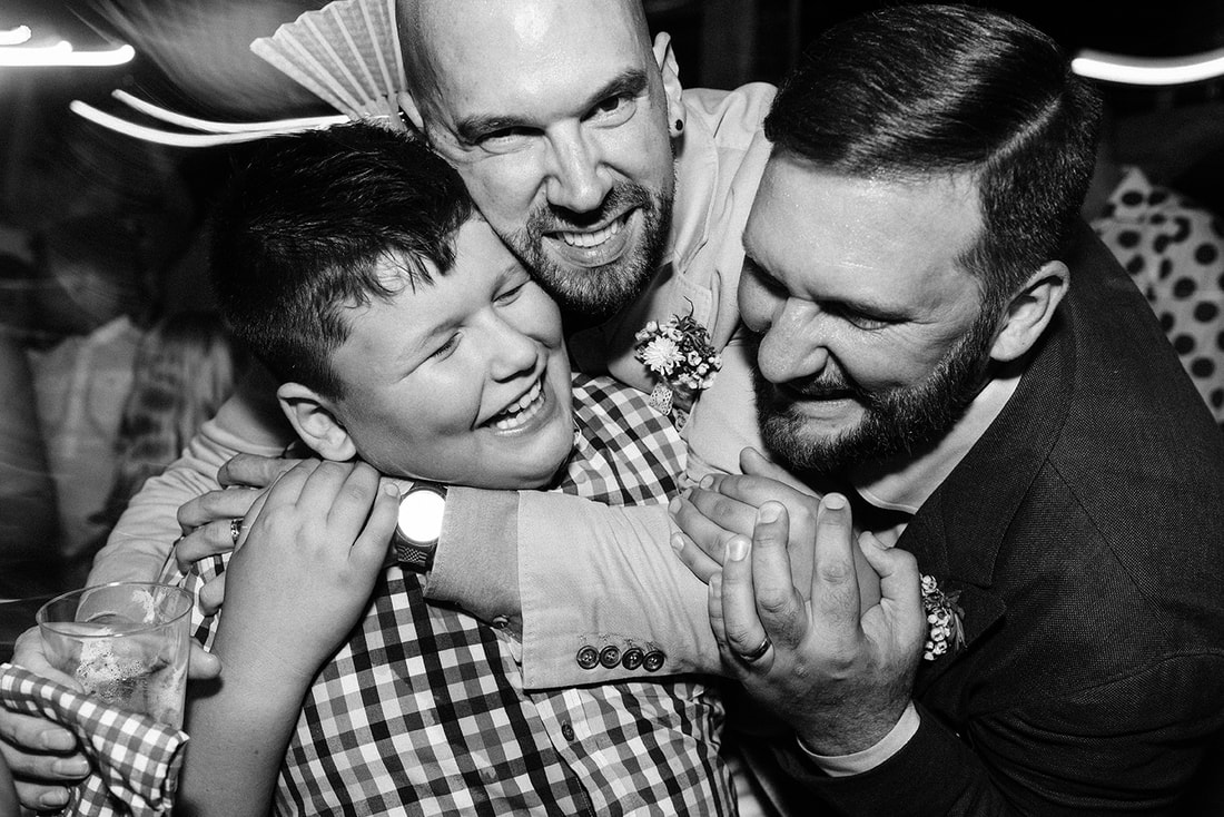 two men hugging a young boy all are smiling