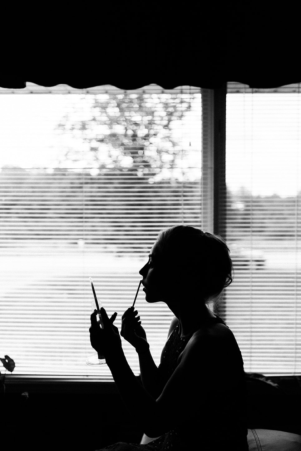 silhouette of woman applying lipstick 